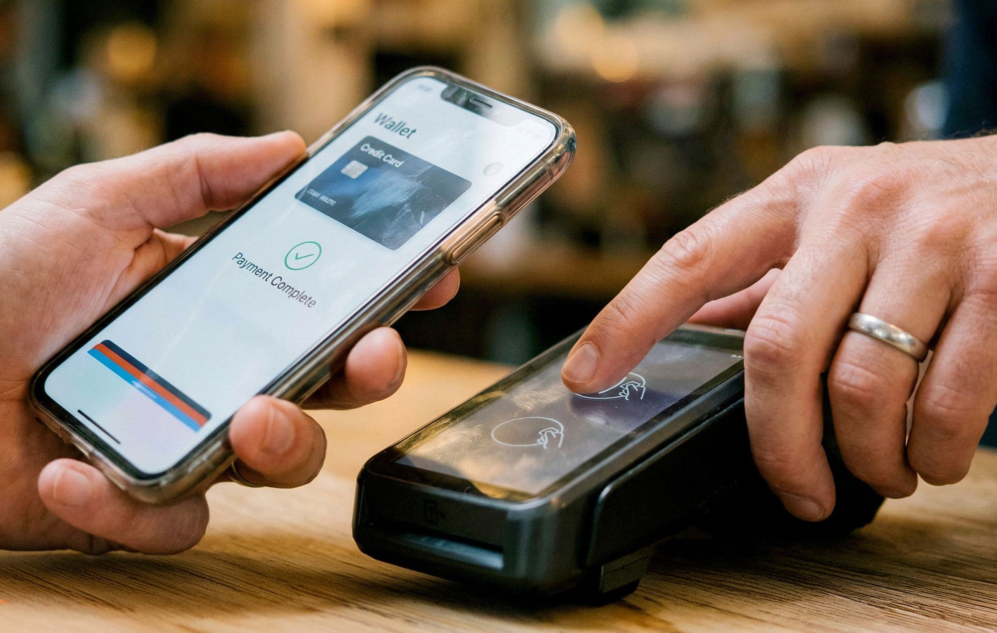 Inside Today's Payment Preferences: Person holding a smartphone showing a digital wallet payment complete screen while tapping a contactless card reader