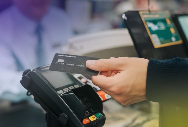 Hand tapping a payment card at a checkout register.